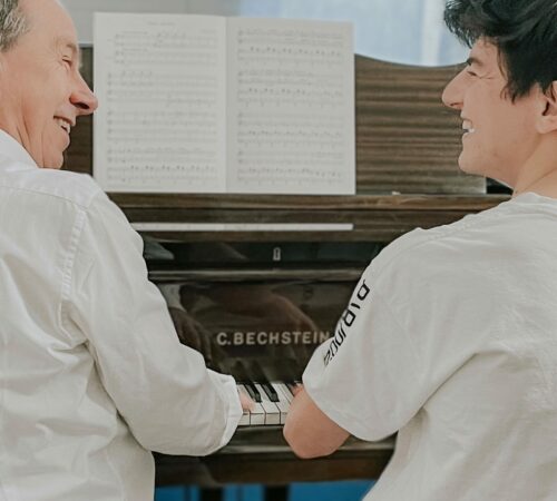 Klavierlehrer und Klavierschüler spielen gemeinsam Klavier