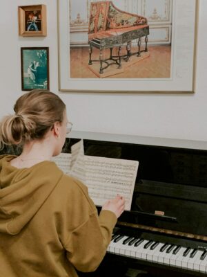 Schülerin sitzt am Klavier und blaettert Noten um