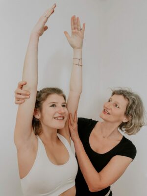 Frau macht Yoga Entspannungsübung und Yogalehrerin hilft